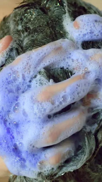 Hands in hair with purple shampoo suds and bubbles